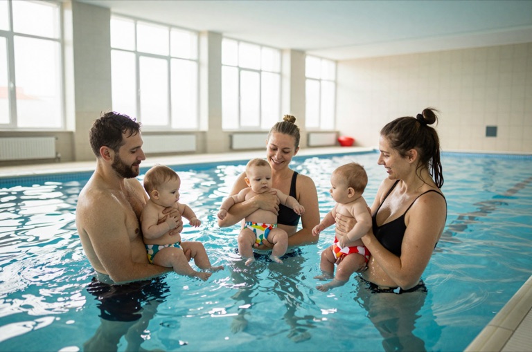 Eltern mit Babys im warmen Wasser eines Lehrschwimmbeckens