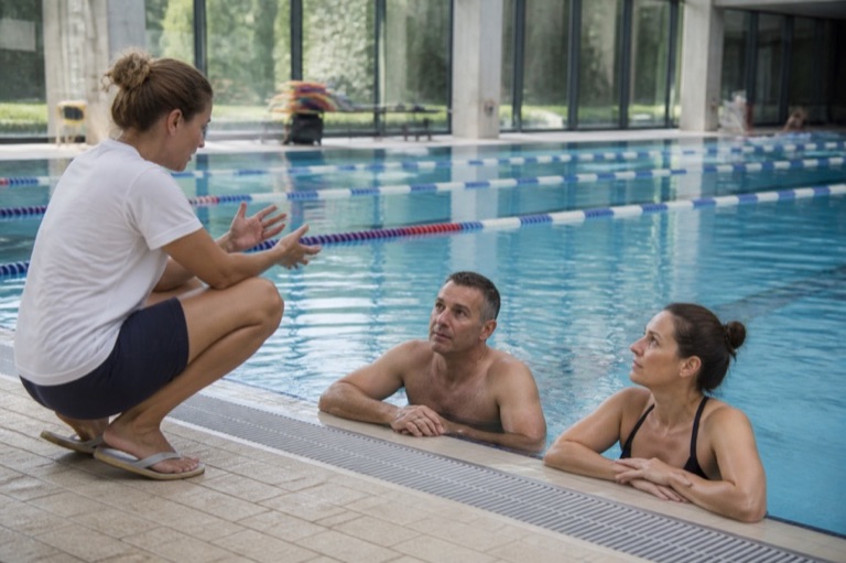 Schwimmbecken mit Bahnen und Schwimmlehrerin am Beckenrand